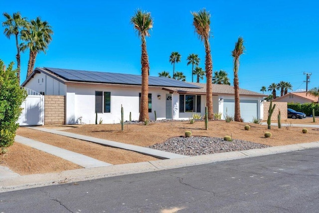 ranch-style home featuring solar panels and a garage