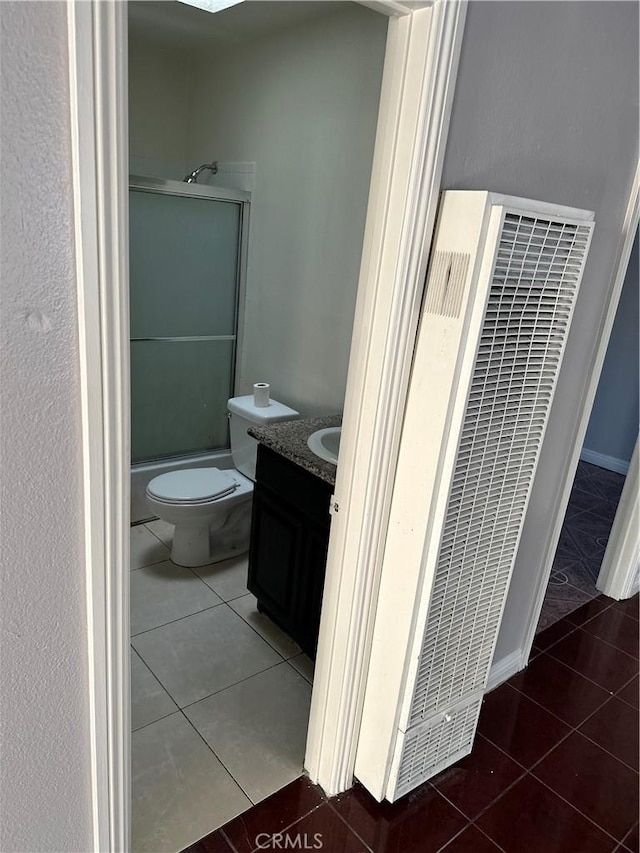 bathroom featuring toilet, vanity, tile patterned floors, and walk in shower