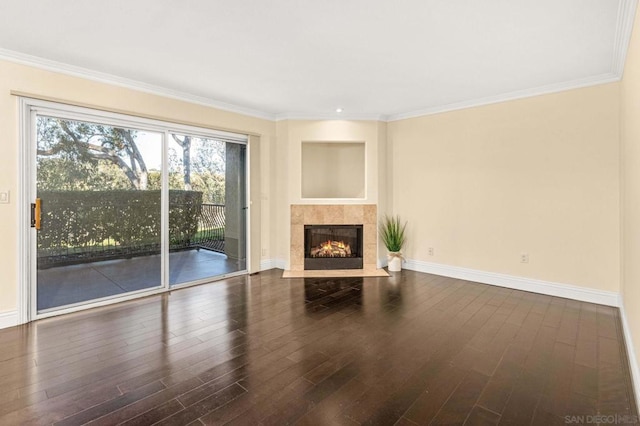 unfurnished living room with a tiled fireplace, crown molding, and dark wood-type flooring