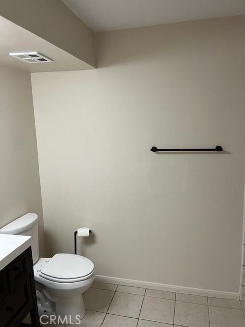 bathroom with toilet, vanity, and tile patterned flooring