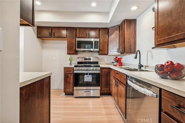 kitchen featuring appliances with stainless steel finishes, light hardwood / wood-style floors, dark brown cabinetry, and sink