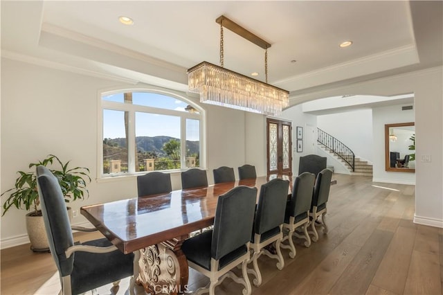 dining room with a raised ceiling, crown molding, a notable chandelier, a mountain view, and hardwood / wood-style floors