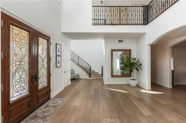 entrance foyer featuring french doors, wood-type flooring, and a high ceiling