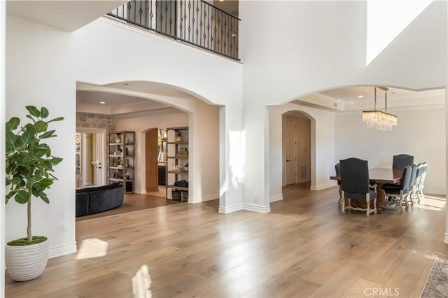 dining area with a notable chandelier, a towering ceiling, and light hardwood / wood-style flooring