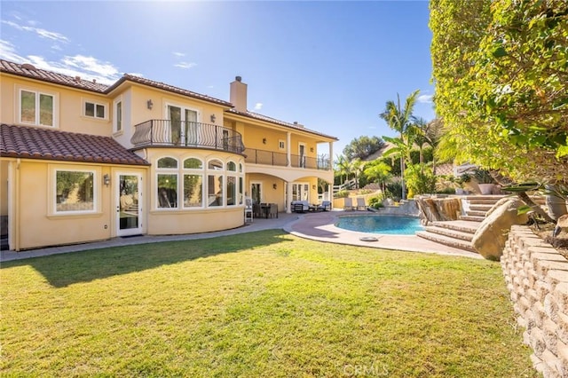 rear view of house featuring a yard, pool water feature, a balcony, and a patio