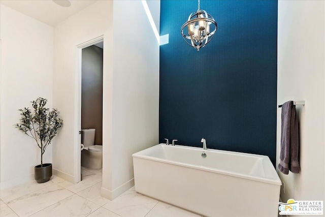 bathroom with toilet, a chandelier, and a bath