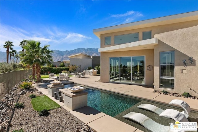 back of house featuring a mountain view, a fire pit, and a patio