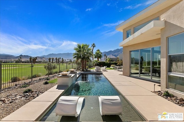 view of pool featuring a mountain view, pool water feature, and a patio