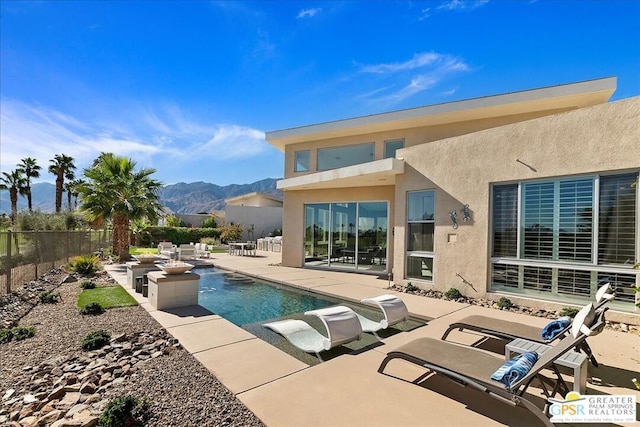 rear view of property featuring a fenced in pool, a patio area, and a mountain view