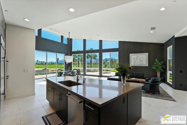 kitchen featuring a wealth of natural light, sink, dishwasher, and an island with sink