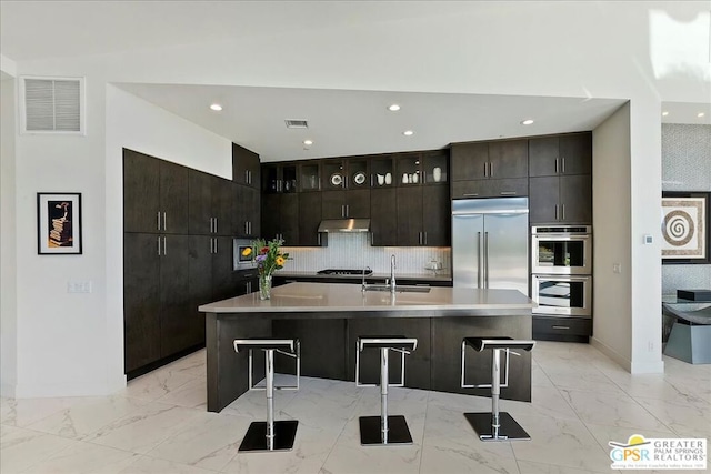 kitchen with sink, a kitchen breakfast bar, appliances with stainless steel finishes, and a kitchen island with sink