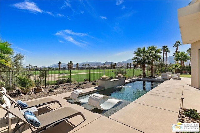 view of swimming pool featuring pool water feature, a mountain view, and a patio