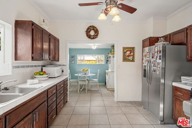 kitchen with ceiling fan, sink, stainless steel refrigerator with ice dispenser, and ornamental molding