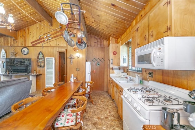 kitchen with vaulted ceiling with beams, white appliances, wood walls, and wood ceiling