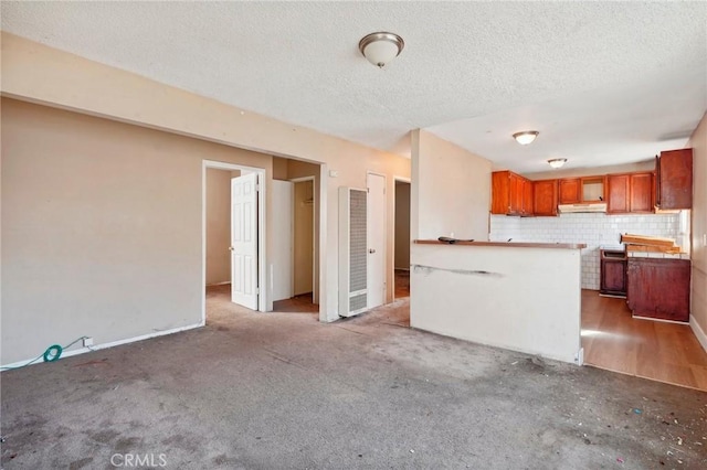 kitchen featuring backsplash, kitchen peninsula, carpet floors, and a textured ceiling