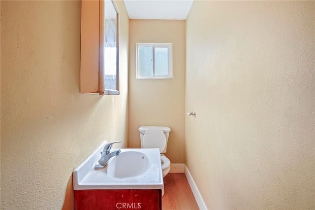 bathroom with toilet, vanity, and hardwood / wood-style flooring