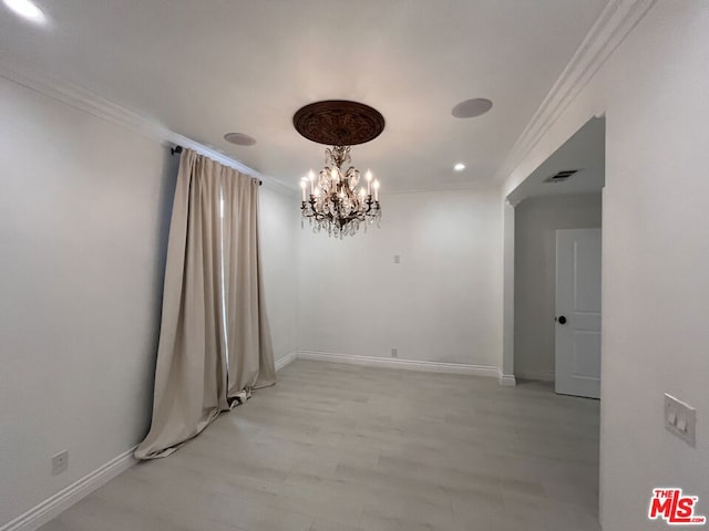 spare room featuring ornamental molding, light hardwood / wood-style floors, and a notable chandelier