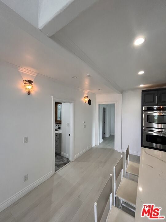 kitchen with light stone countertops, light hardwood / wood-style floors, and double oven