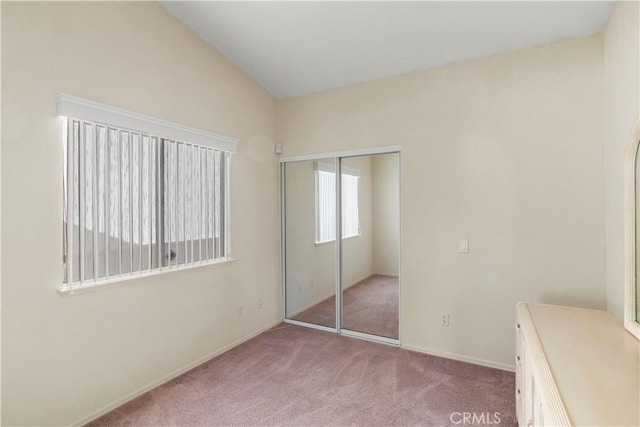 unfurnished bedroom featuring light carpet, a closet, and lofted ceiling