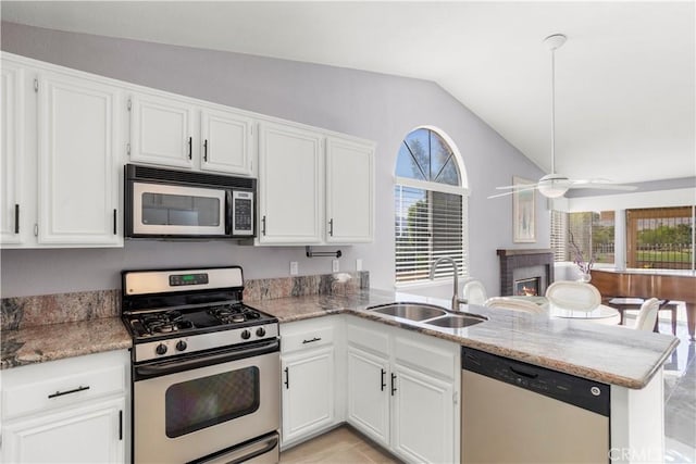 kitchen with kitchen peninsula, appliances with stainless steel finishes, sink, white cabinetry, and lofted ceiling