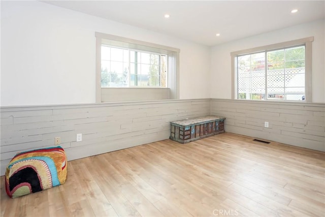 empty room with light hardwood / wood-style flooring and wood walls