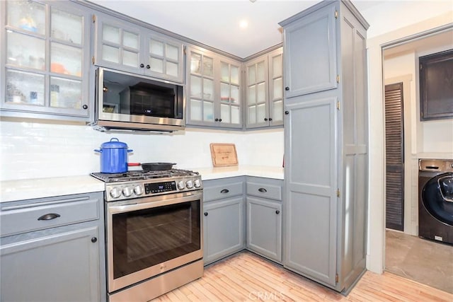 kitchen featuring light hardwood / wood-style flooring, appliances with stainless steel finishes, washer / dryer, and gray cabinetry