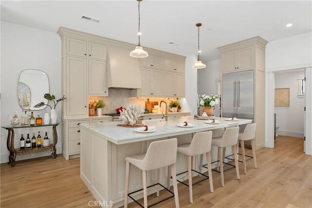 337 Holmwood Dr, Newport Beach, CA 92663 - kitchen with custom exhaust hood, built in fridge, tasteful backsplash, a breakfast bar, and pendant lighting