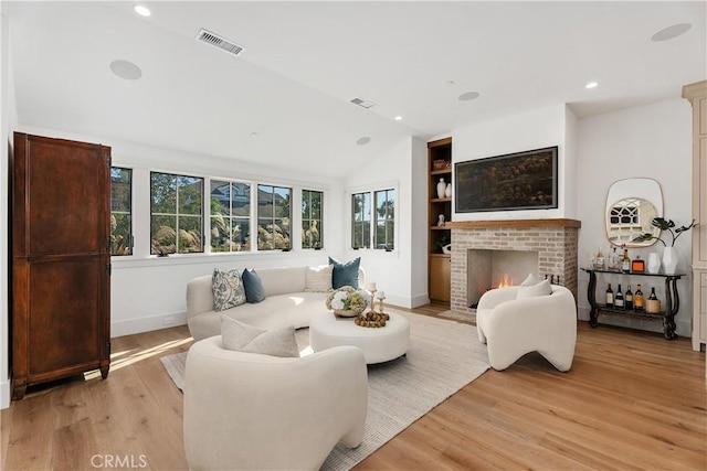 living room with a healthy amount of sunlight, light hardwood / wood-style floors, and vaulted ceiling