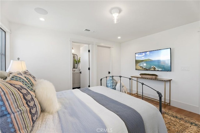 bedroom with ensuite bathroom and hardwood / wood-style flooring