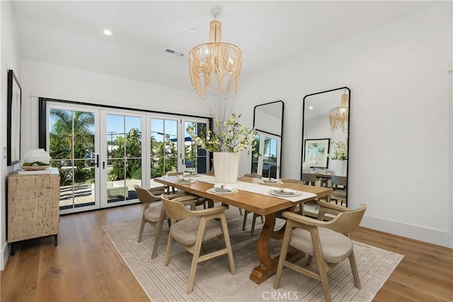 dining room with french doors, wood-type flooring, and an inviting chandelier