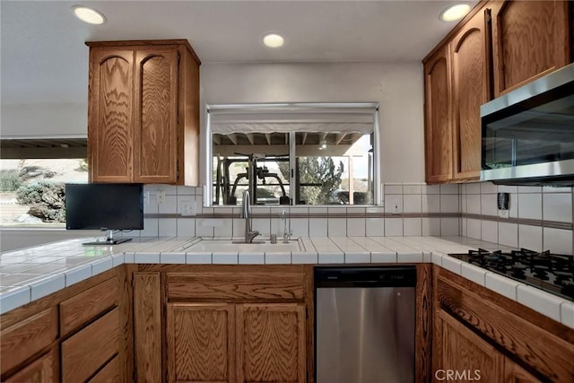 kitchen featuring decorative backsplash, appliances with stainless steel finishes, tile countertops, and sink