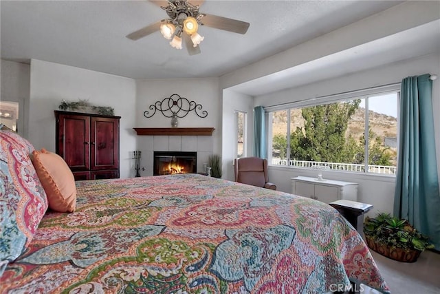 bedroom with a tiled fireplace and ceiling fan