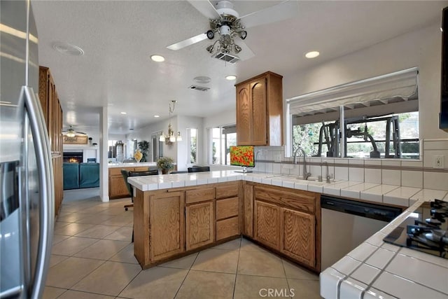 kitchen featuring tile countertops, plenty of natural light, kitchen peninsula, and stainless steel appliances