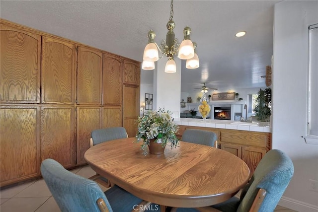 tiled dining area featuring sink, ceiling fan with notable chandelier, and a textured ceiling