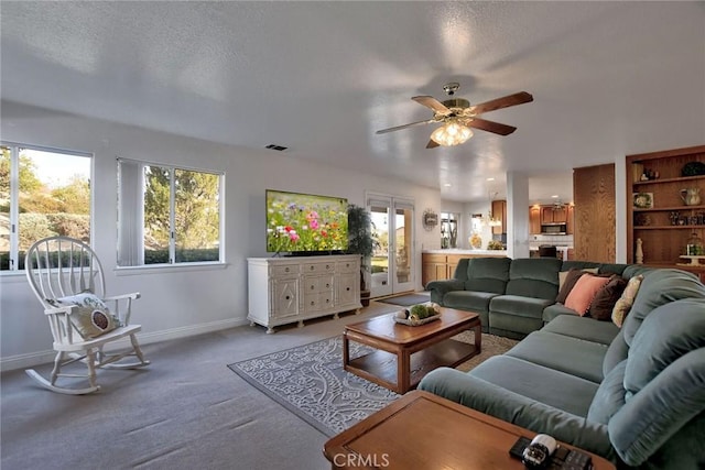 carpeted living room with ceiling fan and a textured ceiling