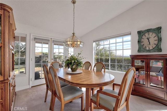 dining area featuring a chandelier, light colored carpet, and vaulted ceiling