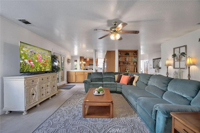 carpeted living room with ceiling fan and a textured ceiling