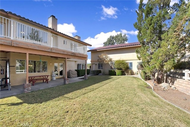 back of property with a yard and a patio