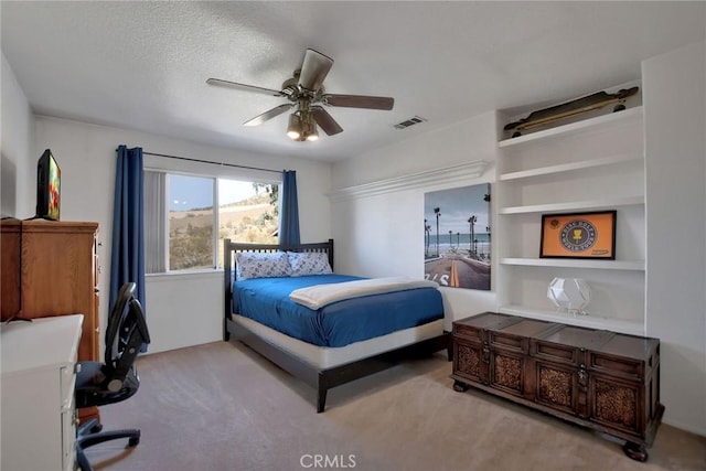 carpeted bedroom featuring ceiling fan and a textured ceiling