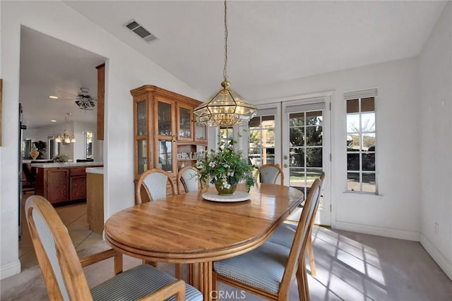 dining room with ceiling fan with notable chandelier and vaulted ceiling