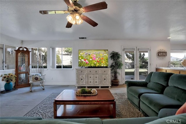 living room featuring ceiling fan, light colored carpet, a textured ceiling, and a wealth of natural light