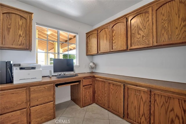 kitchen featuring light tile patterned flooring, built in desk, and a textured ceiling