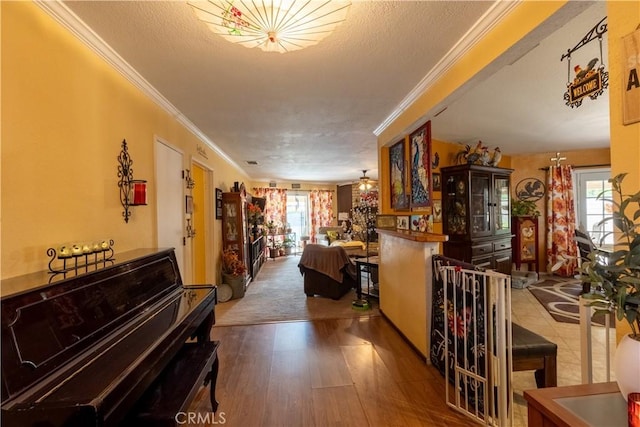 hallway featuring crown molding, wood-type flooring, a textured ceiling, and plenty of natural light