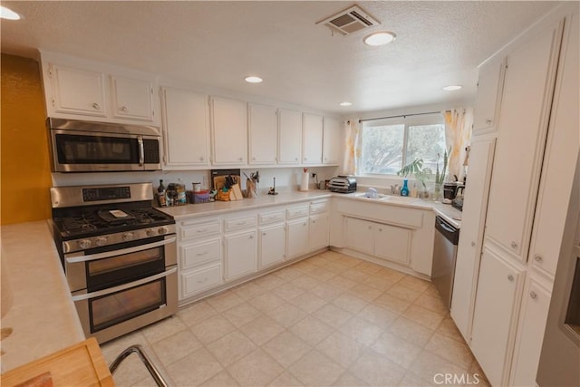 kitchen featuring stainless steel appliances, sink, white cabinets, and a textured ceiling