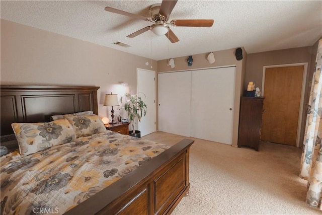 bedroom featuring light colored carpet, a textured ceiling, ceiling fan, and a closet