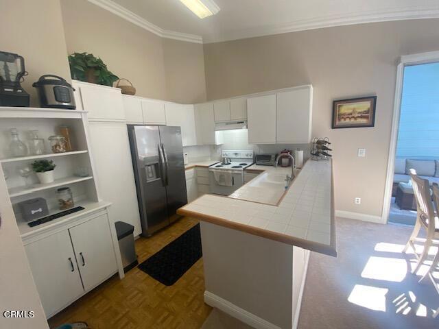 kitchen featuring kitchen peninsula, tile countertops, white electric stove, white cabinets, and stainless steel fridge with ice dispenser