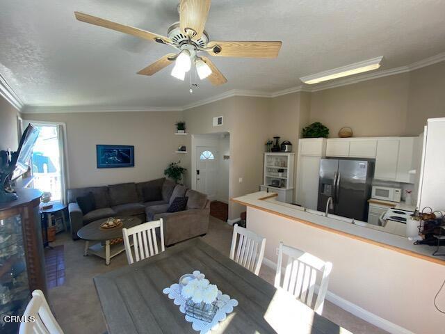 carpeted dining space featuring ceiling fan and crown molding