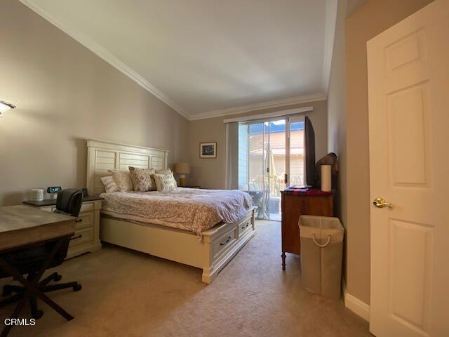 bedroom with light carpet, vaulted ceiling, and ornamental molding