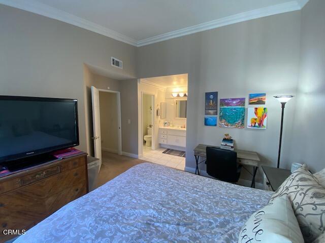 bedroom featuring connected bathroom and crown molding