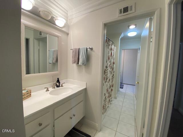 bathroom featuring vanity, tile patterned floors, walk in shower, and ornamental molding